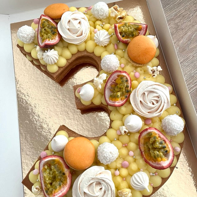 number cake chiffre 3 avec un lemon curd et en décoration des fruits de la passion, des meringues et des macarons.
